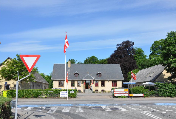 Ugerløse Beboer- og Kulturhus set fra Hovedgaden med flag ved indgangen